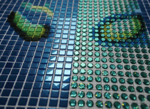 a detailed close-up comparison between square and round diamond drills on a half-finished canvas